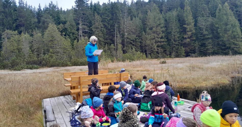 Lehrerin liest am See die Sage vom Drachen vor.